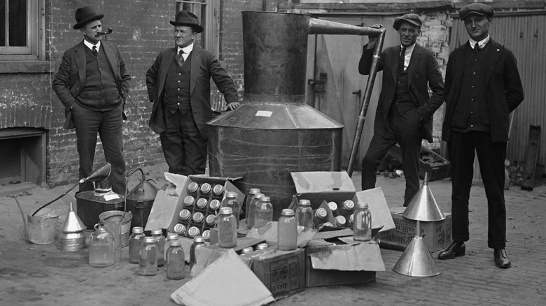 Vintage black and white photo of men in suits with boxes of bottles