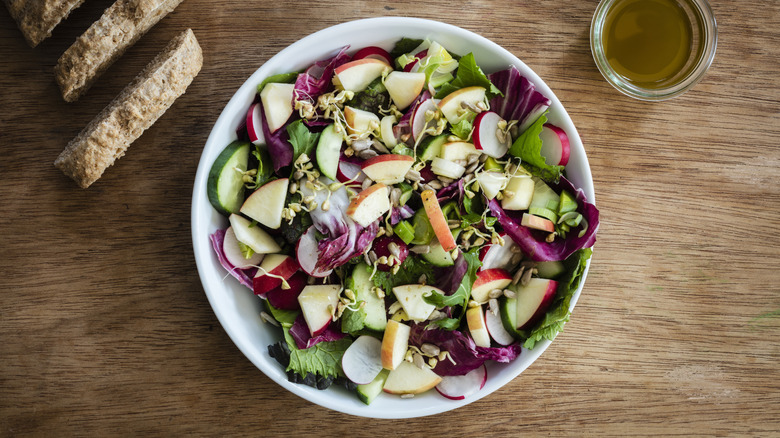 Salad with fruits and greens and a side of bread