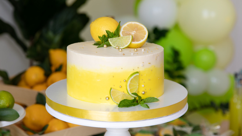 Cake decorated with yellow frosting and lemons and limes