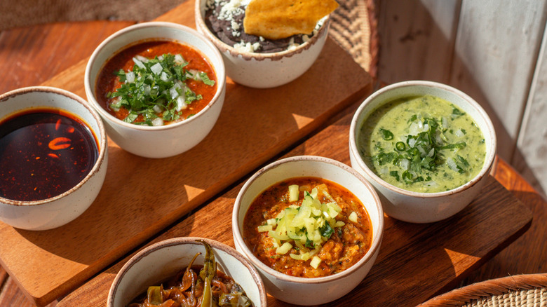 Different types of salsas and dips on wooden table