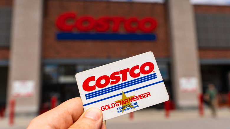 Costco card being held up against storefront