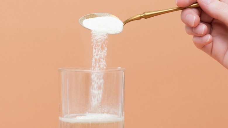 Powder being sprinkled from a spoon into a glass