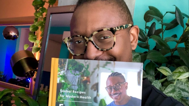 Gregory Gourdet holding up his cookbook