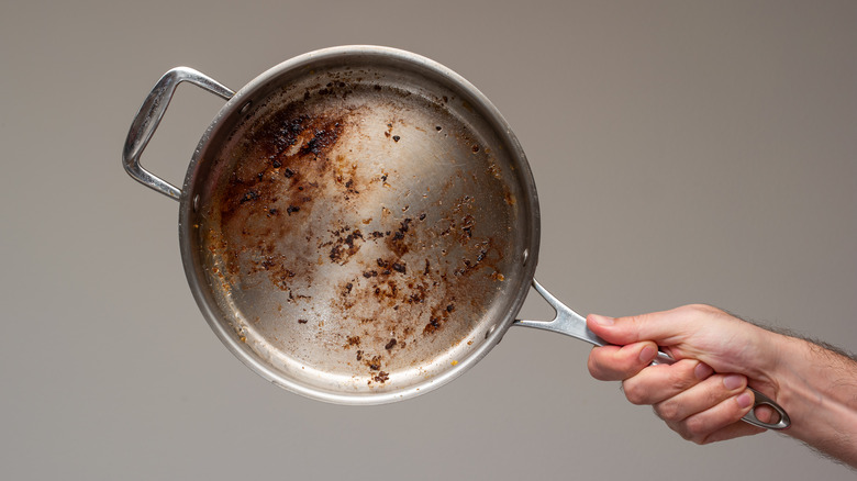 Person holding stainless steel pan with residue on it