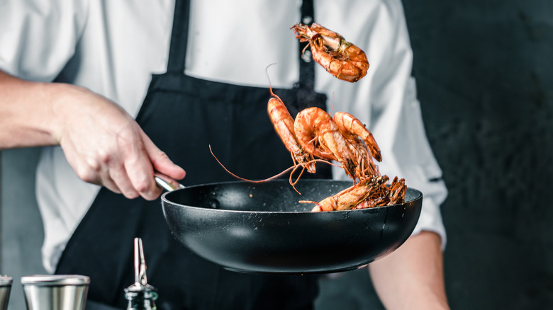chef cooking shrimp in skillet