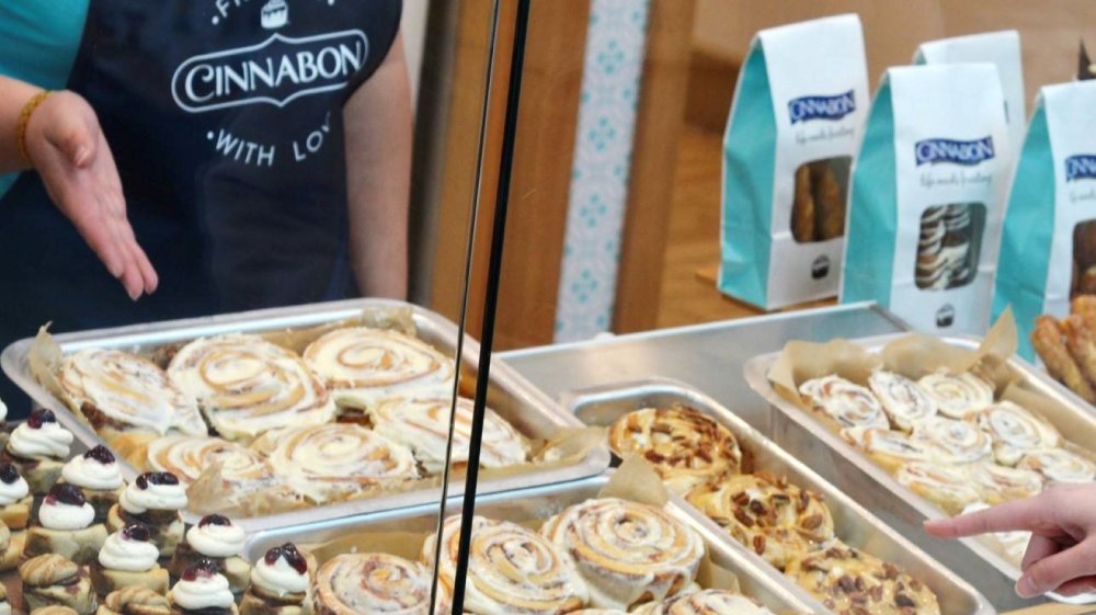 Customer shopping for fresh Cinnabon products in a window display case