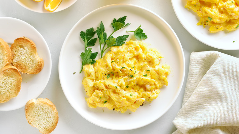 Scrambled eggs on white plate with side of toast
