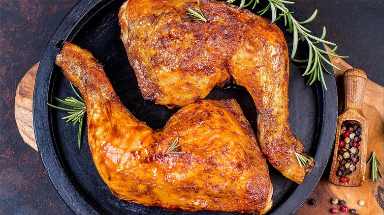 Chicken thighs on a black plate with rosemary