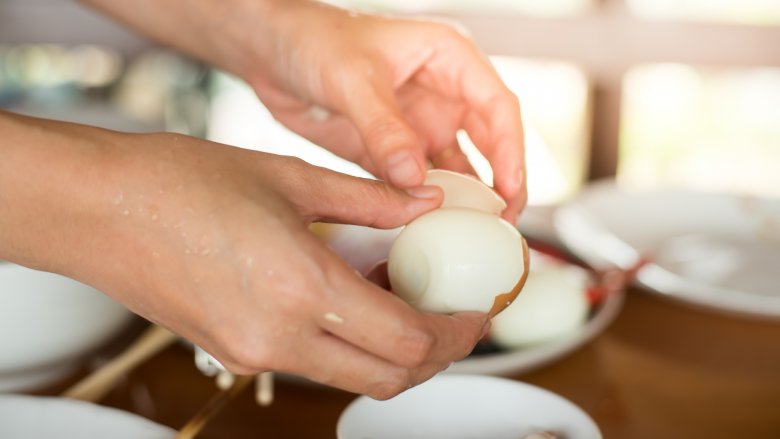 woman peeling hard-boiled egg
