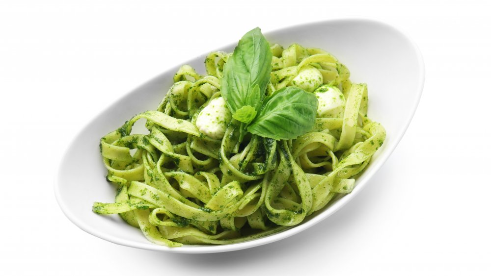 Fettuccine pasta in pesto sauce on a white background.