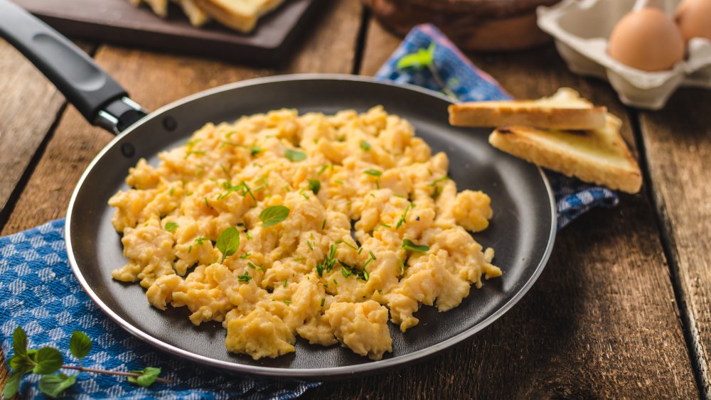 Plate of scrambled eggs with herbs and toast on the side