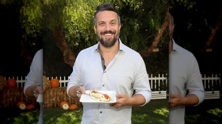 Fabio Viviani smiling and holding a plate of food