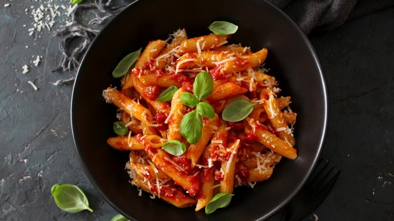 Bowl of pasta with tomato sauce, cheese, and basil