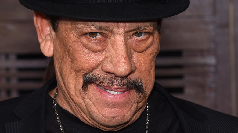 Danny Trejo wearing hat and chain necklace