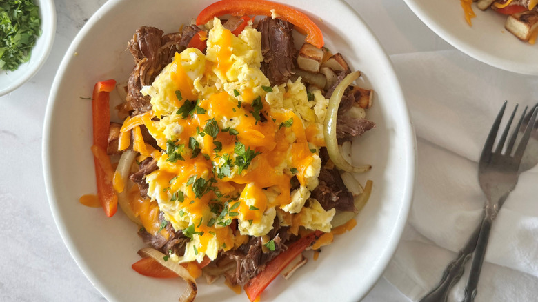 scrambled eggs, meat, vegetables, and cheese in a white bowl