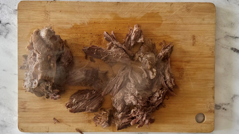 partially shredded beef on a wooden board