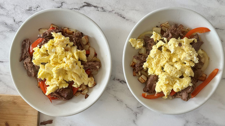 scrambled eggs, meat, and vegetables in two white bowls