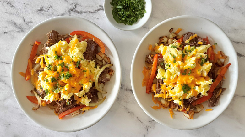 scrambled eggs, meat, vegetables, and cheese in two white bowls