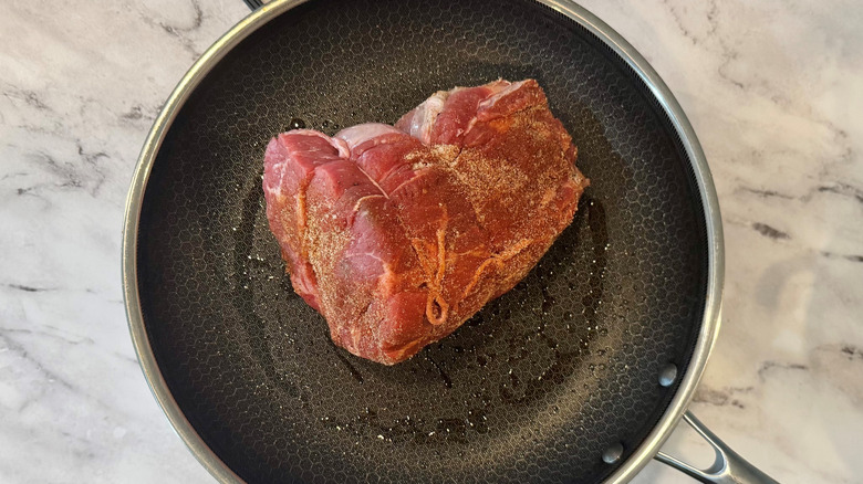 raw meat in a black frying pan