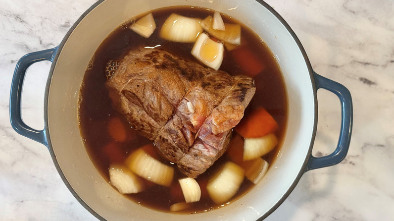 meat, vegetables, and liquid in a white pot