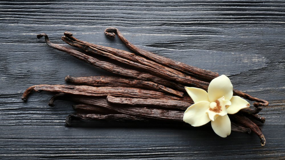 vanilla bean pods and flower on a wooden background