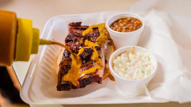 Squirting sauce on ribs with beans and slaw