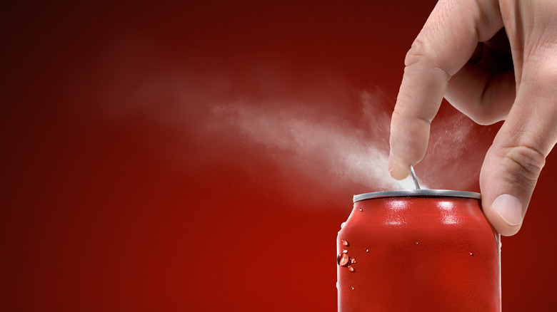 Hand opening a soda on red background