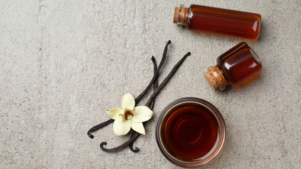 Vanilla bean next to bowl of extract