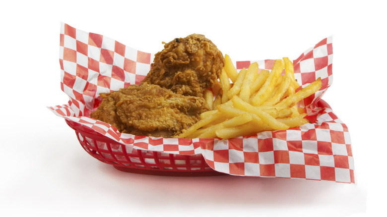 Fried chicken and french fries in a basket with red and white chekered paper