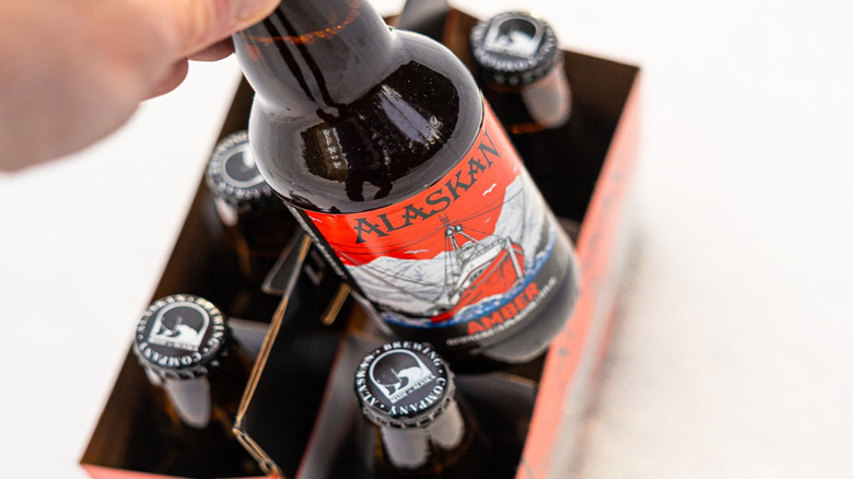 hand pulling a bottle of Alaskan Amber from a six pack