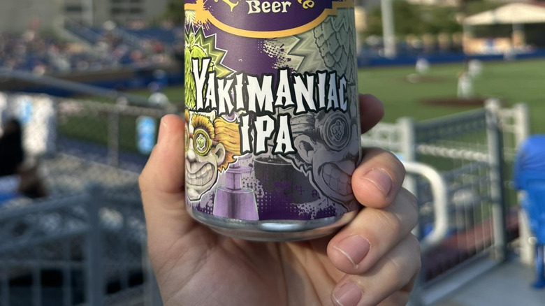 hand holding a Yakimaniac IPA can at a ballpark