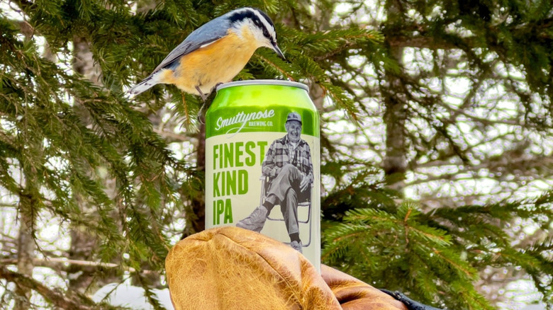 gloved hand holding a Finest Kind can with a bird on it
