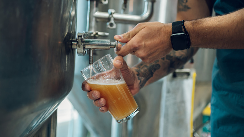Person pouring beer from a tap into a glass in a brewery