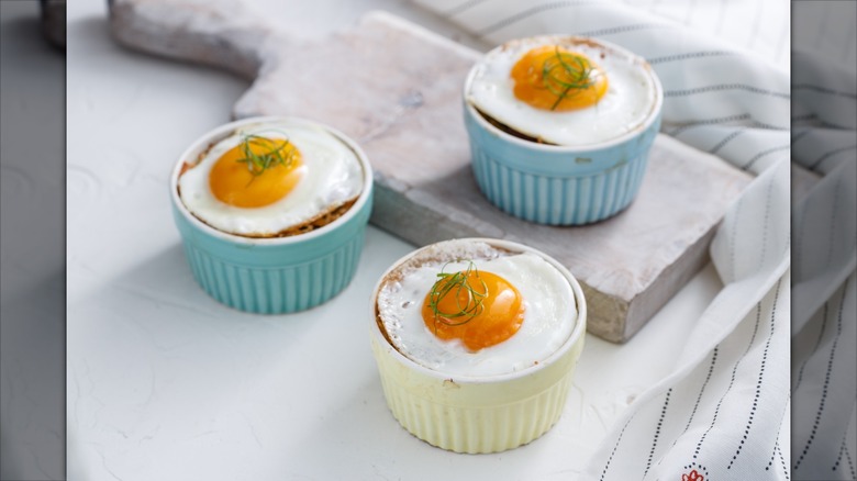 Three baked eggs in individual ramekins topped with herbs