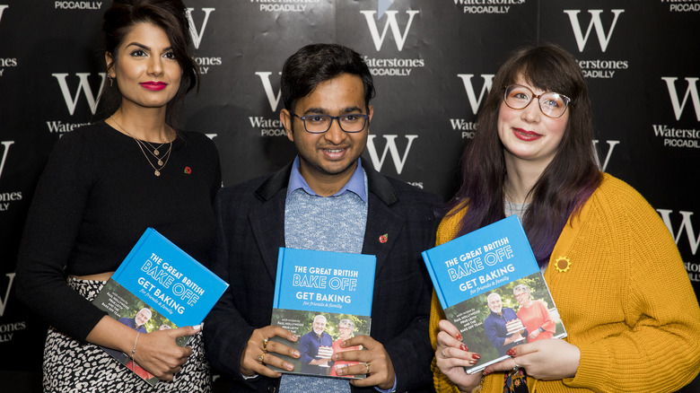 Former GBBO contestants holding cookbooks 