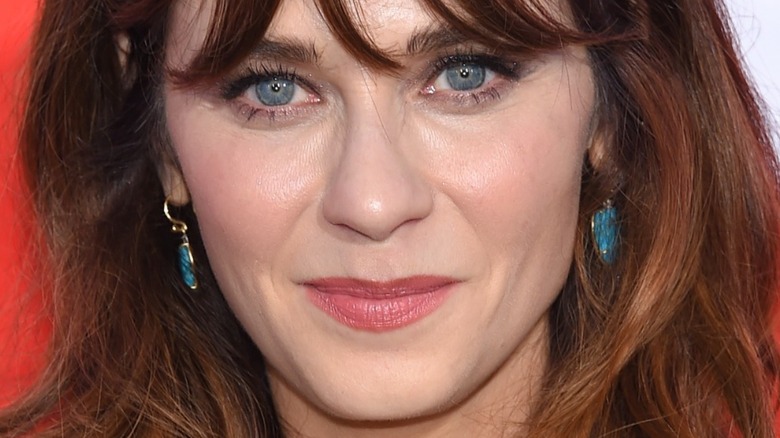 Zooey Deschanel with slight smile wearing blue earrings