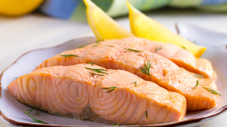 Poached salmon fillets with lemon wedges