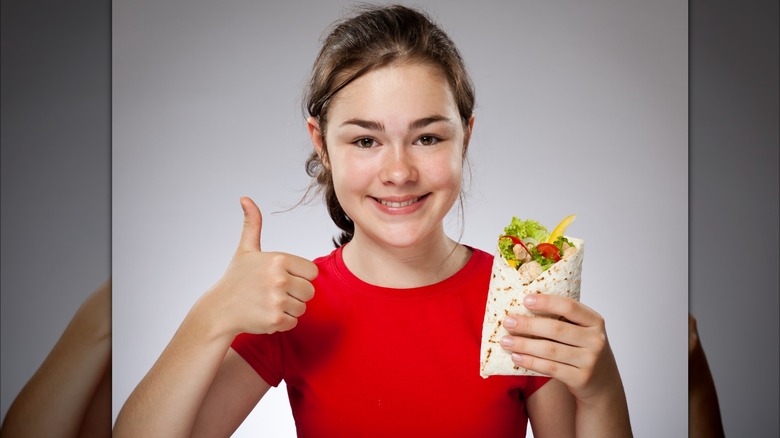 child with burrito and thumbs-up
