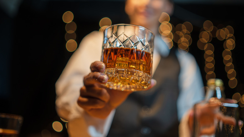 Server handing a bourbon glass to patron