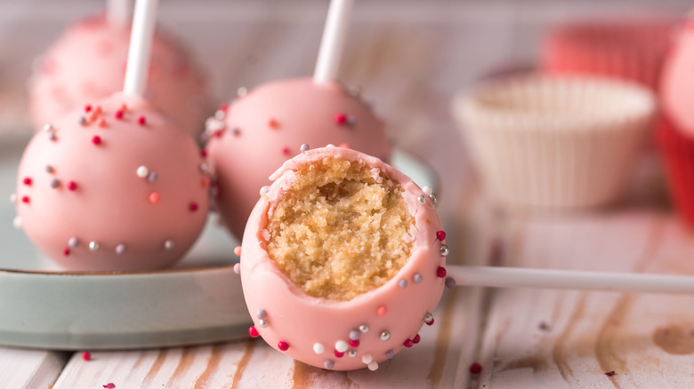 pink cake pops with sprinkles, pink cupcake liners in background
