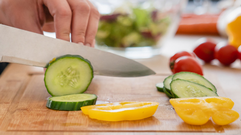 Chopping cucumber and pepper veggies with knife