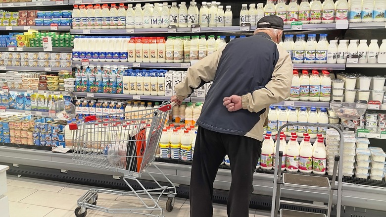 man looking at milk in grocery store