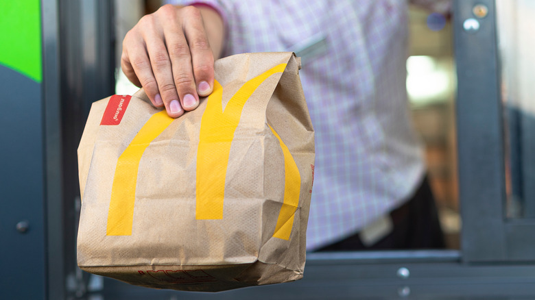 Someone handing someone a bag of McDonald's at a drive thru