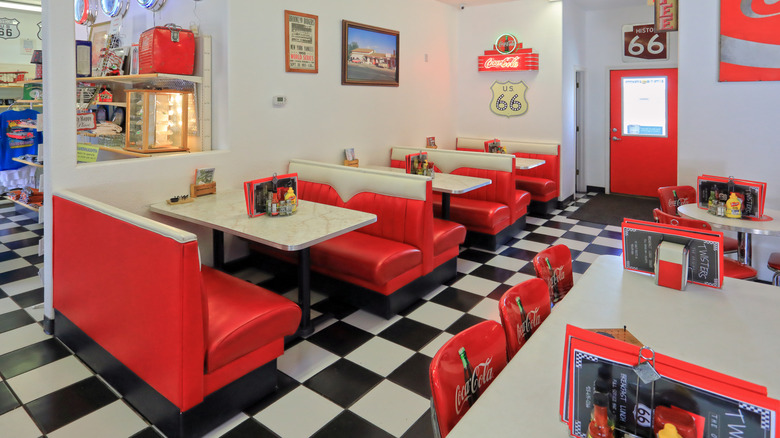 Interior of 1950s-style diner, with checked floors and red booths