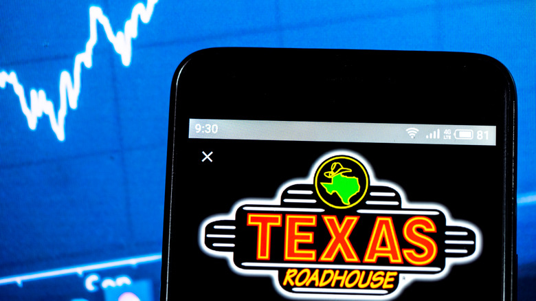 Texas Roadhouse logo on phone with rising graph in background