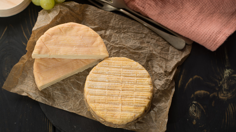 cutting open a wheel of washed rind cheese
