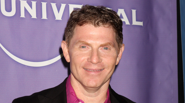 Bobby Flay wearing a purple shirt and black jacket