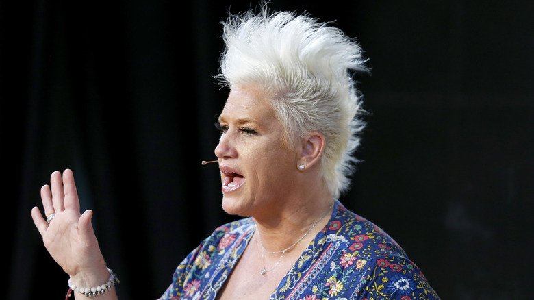 Anne Burrell speaking on stage at an event