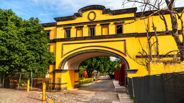 A yellow archway over a cobblestone street, the exterior of La Rojeña distillery.