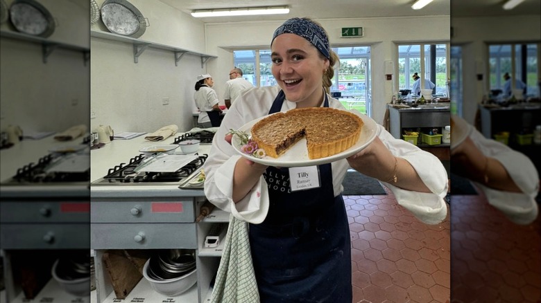 Tilly Ramsay holding up a pie at culinary school
